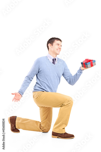 Photo: Smiling male practicing a proposal and holding a gift box Smiling male practicing a proposal and holding a gift box