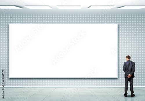 Photo: Business person standing near a blank billboard Business person standing near a blank billboard