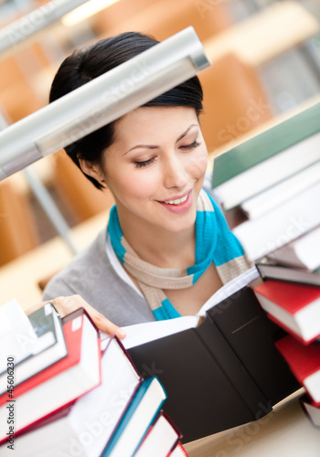 Photo: Reading book female student surrounded with piles of books Reading book female student surrounded with piles of books