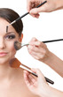 Photo: Three hands of makeup artists applying cosmetics on face Three hands of makeup artists applying cosmetics on face