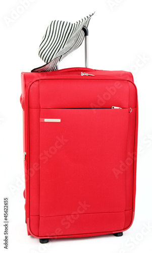 Photo: Red suitcase with female sun hat, isolated Red suitcase with female sun hat, isolated