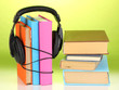Headphones on books on green background