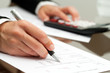 Close up of hand with pen on accounting document.
