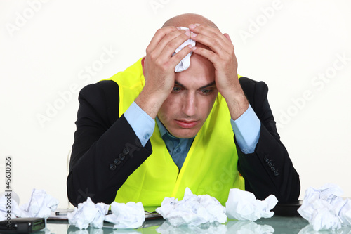 Photo: Man with a desk full of screwed up paper Man with a desk full of screwed up paper