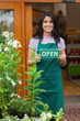 Woman holding open sign at entrance to garden center
