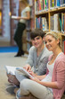 Man and woman sitting in front of a bookshelf while smiling