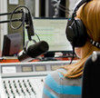 Rear view of female dj working in front of a microphone