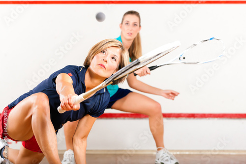 Photo: Squash sport - women playing on gym court Squash sport - women playing on gym court