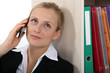 Businesswoman leaning against bookcase during call