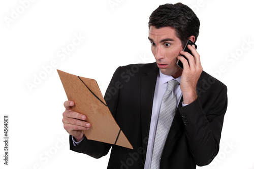 Photo: Shocked man looking at a file folder Shocked man looking at a file folder