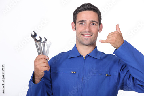 Photo: Man with spanners making a call me sign with his hand Man with spanners making a call me sign with his hand