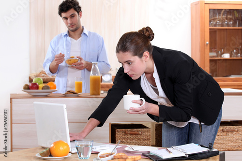 Photo: Woman working while eating breakfast Woman working while eating breakfast