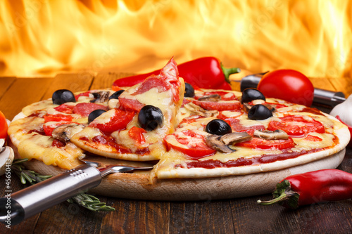 Photo: Hot pizza with oven fire on background Hot pizza with oven fire on background
