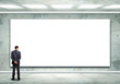 Business person standing near a blank billboard
