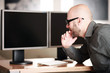 Mann im Büro vor PC Bildschirmen