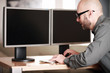 Mann im Büro vor PC Bildschirmen