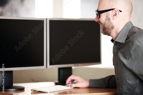 Photo: Mann im Büro vor PC Bildschirmen Mann im Büro vor PC Bildschirmen