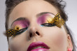 girl with feathered makeup looks down at left