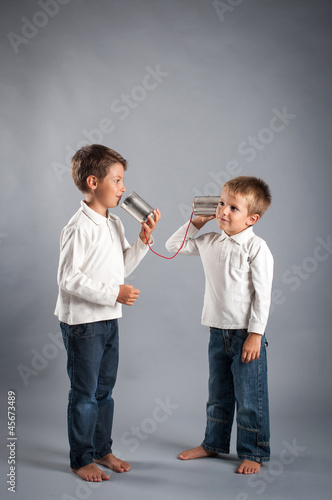 Photo: Young brothers talking with tin can telephone. Young brothers talking with tin can telephone.