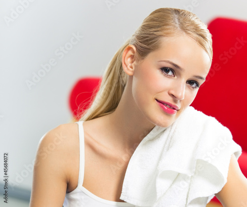 Photo: Cheerful woman in fitness wear with towel, at home Cheerful woman in fitness wear with towel, at home