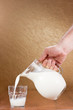 Hand pouring milk from jug to glass