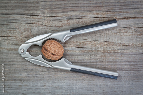 Photo: Nutcracker and walnuts on wooden texture coating. Nutcracker and walnuts on wooden texture coating.