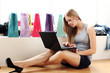 Woman with laptop on hands and shopping bags behind her