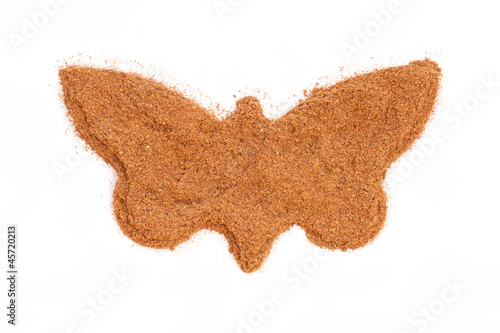 Photo: Heap of ground Cinnamon isolated in butterfly shape on white bac Heap of ground Cinnamon isolated in butterfly shape on white bac