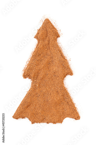 Photo: Heap of ground Cinnamon isolated in christmas tree shape on whit Heap of ground Cinnamon isolated in christmas tree shape on whit