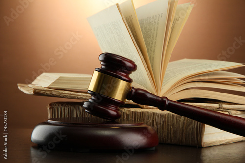 Photo: wooden gavel and books on wooden table,on brown background wooden gavel and books on wooden table,on brown background