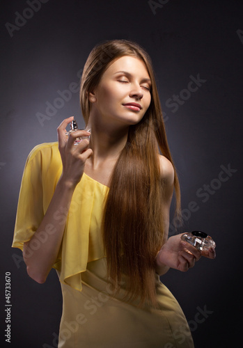 Photo: beautiful young woman spraying perfume beautiful young woman spraying perfume