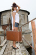 The beautiful young woman with a suitcase at a pier