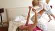 Mother Giving Daughter Ride On Feet Whilst Lying On Bed