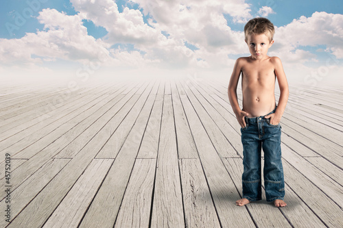 Photo: Young kid standing on a wood floor with cloudy blue sky. Young kid standing on a wood floor with cloudy blue sky.