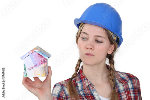 Photo: worker holding a miniature of a house made of bills worker holding a miniature of a house made of bills