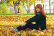 Portrait of a beautiful woman sitting on fall leaves