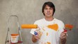 Surprised man holding paintbrushes and showing confuse