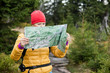 Woman hiking and reading map in forest