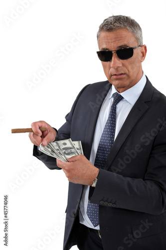 Photo: Businessman with a cigar and a fistful of dollars Businessman with a cigar and a fistful of dollars
