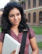 Young Indian / Asian college student holding  a laptop computer.