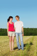 Husband, wife stand in field look at each other