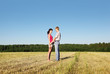 Husband hold hands wife and look on she in field, side
