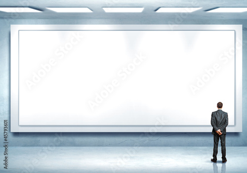 Photo: Business person standing near a blank billboard Business person standing near a blank billboard