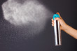 Sprayed air freshener in hand on grey background