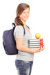 A smiling schoolgirl holding books and green apple