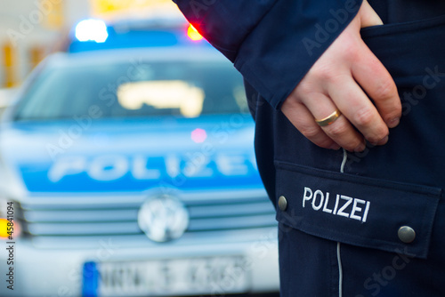 Photo: Polizist vor Polizeiauto Polizist vor Polizeiauto