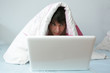 junger mann mit laptop im bett