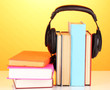 Headphones on books on orange background