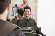A male hairdresser showing his client his new haircut