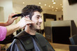 Photo: A male hairdresser cutting his male clients hair with scissors A male hairdresser cutting his male clients hair with scissors